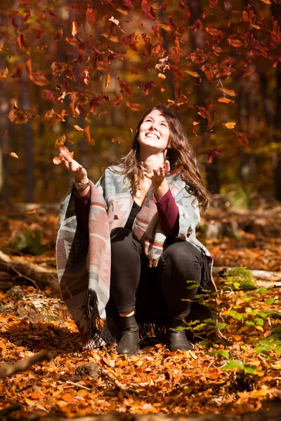 Jovem mulher jogando folhas no ar — Fotografia de Stock
