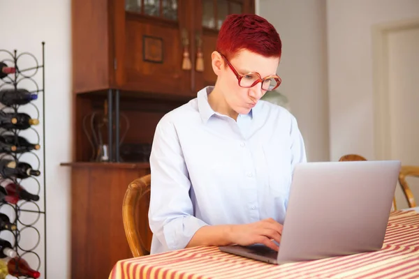 Женщина сидит дома и печатает на ноутбуке — стоковое фото
