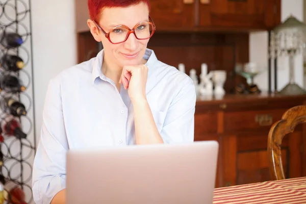 Rödhårig kvinna sitter hemma med sin laptop — Stockfoto