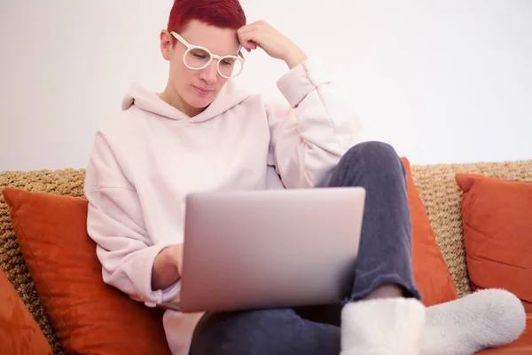 Kvinnan sitter på soffan med sin bärbara dator — Stockfoto