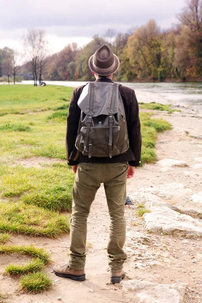 Backside of bavarian man with backpack and standing by river — Stock Photo, Image