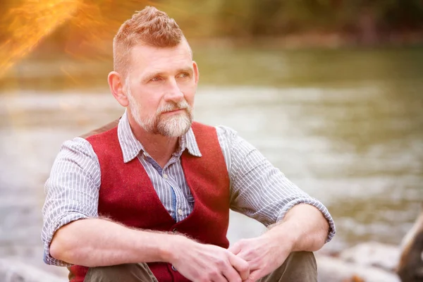 Nehir kenarında oturan 50'li adam portresi — Stok fotoğraf
