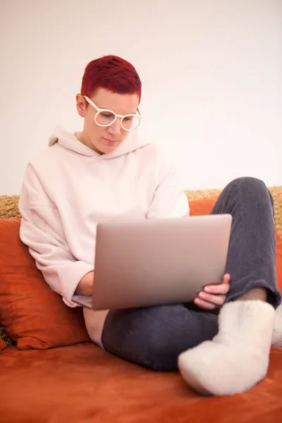 Kvinnan sitter på soffan med sin bärbara dator — Stockfoto