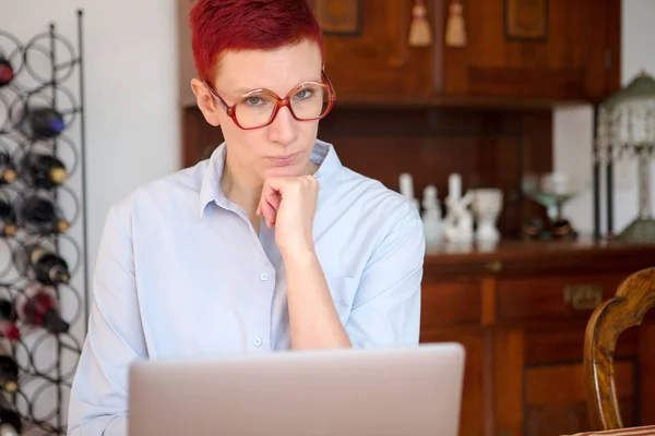 Rödhårig kvinna sitter hemma med sin laptop — Stockfoto