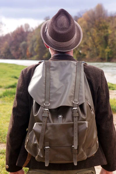 Face arrière de l'homme bavarois avec sac à dos debout près de la rivière — Photo