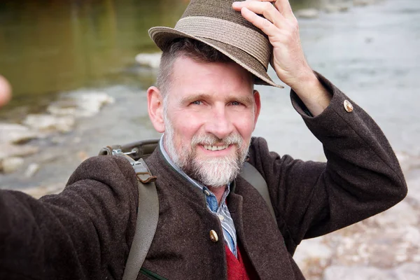 Nehir kenarında duran ve bir selfie alarak 50'li Bavyera adam — Stok fotoğraf