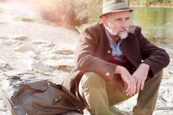 Hombre bavariano en sus 50 años sentado junto al río — Foto de Stock