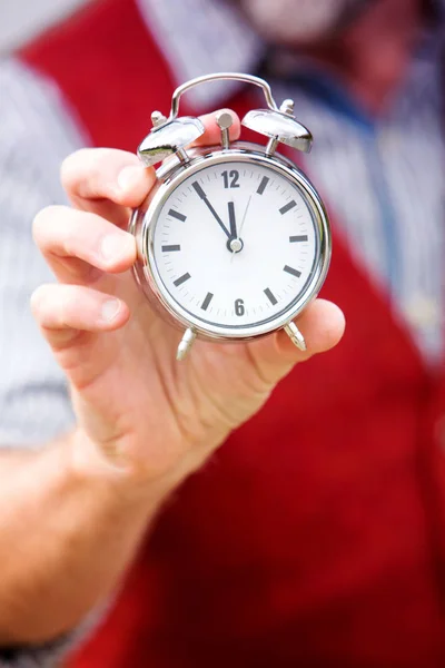Closeup of man in red vest holding a clock — Stock Photo, Image