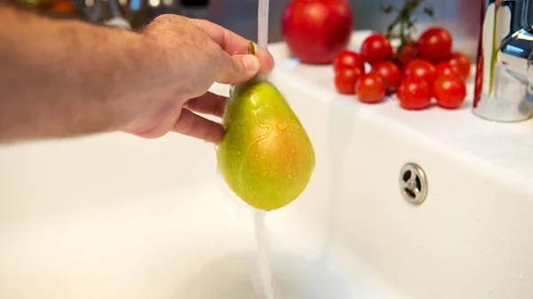 Mão lavando uma pêra fresca na pia — Fotografia de Stock
