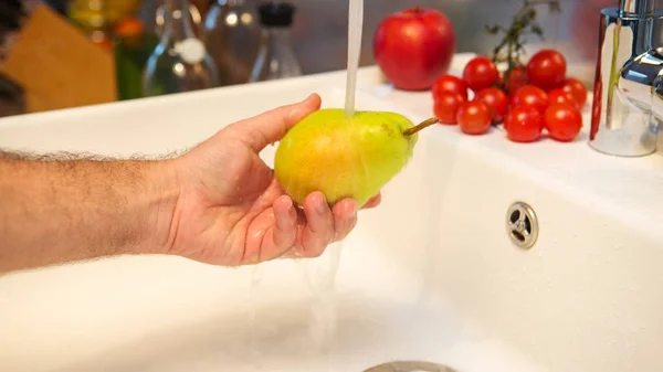 Mão lavando uma pêra fresca na pia — Fotografia de Stock