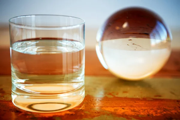 Vidro de água e esfera de vidro na mesa — Fotografia de Stock