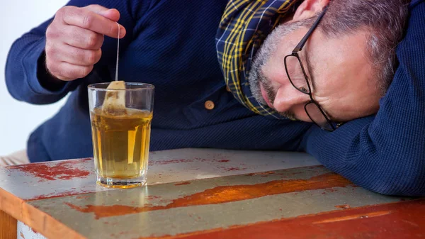 Uomo esausto seduto a tavola con bicchiere di tè — Foto Stock