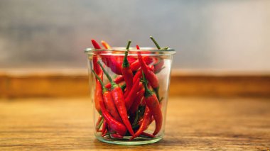 ahşap masa üzerinde bir kavanoza kırmızı chilis