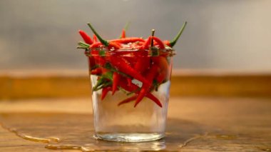 Ahşap masa üzerine su dökerek bir kavanoza kırmızı chilis Cinemagraph