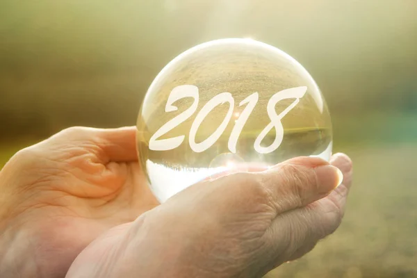 older woman holding glass sphere with 2018