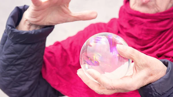 Ältere Frauen halten eine glänzende Glaskugel in der Hand — Stockfoto
