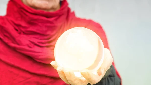 Стара жіноча рука тримає блискучу скляну сферу — стокове фото