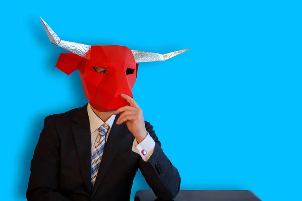 Buisinessman with a bull mask sitting with blue background — Stock Photo, Image