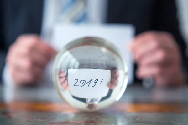 Hombre sosteniendo papel con los números 2019 delante de la bola de vidrio —  Fotos de Stock