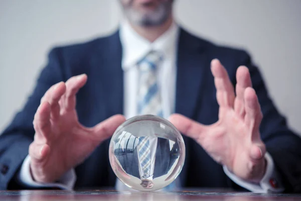 Hombre de negocios mirando la bola de vidrio en la mesa — Foto de Stock