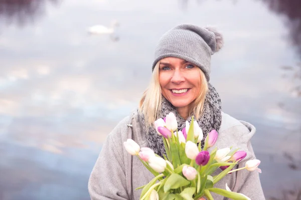 Donna bionda di fronte al lago con tulipani — Foto Stock