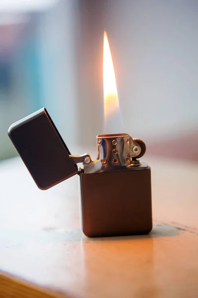 Зажигалка с пламенем на деревянном столе — стоковое фото