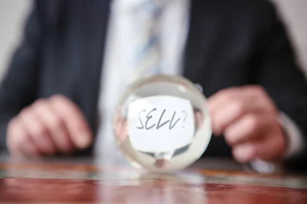 Homem segurando papel com palavra Vender na frente de bola de vidro — Fotografia de Stock