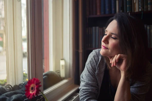 Young woman sitting by the window with her eyes closed — Stock Photo, Image