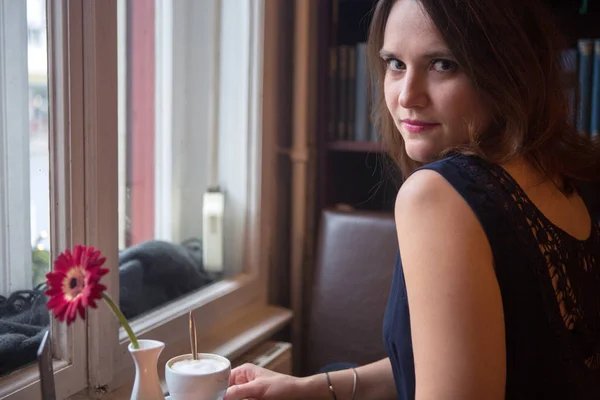 Junge Frau mit Tasse Kaffee am Fenster sitzend — Stockfoto