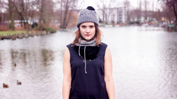 Young woman standing by the water in the cold — Stock Photo, Image