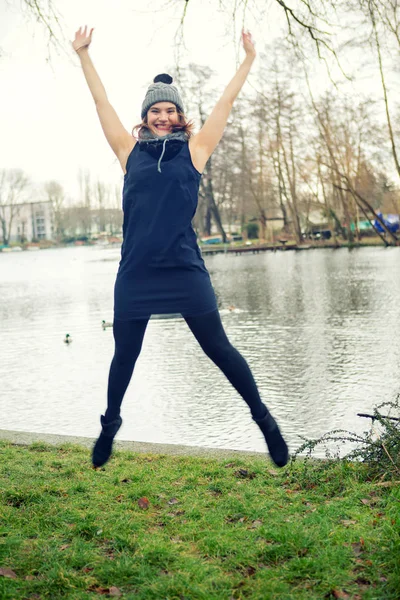 Joven mujer por el agua saltando en el aire — Foto de Stock