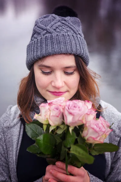 Young woman outdoors with bouquet of pink roses — Stock Photo, Image