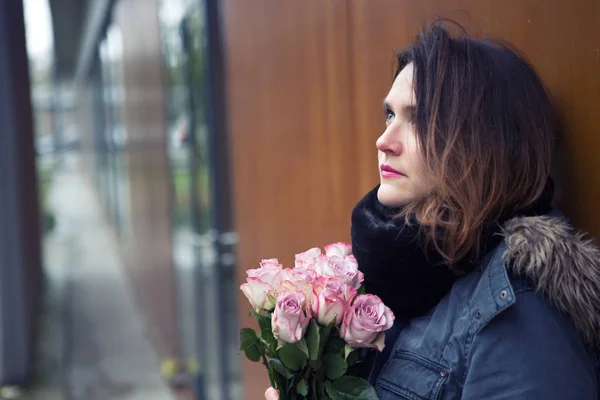 Young woman outdoors with bouquet of pink roses — Stock Photo, Image