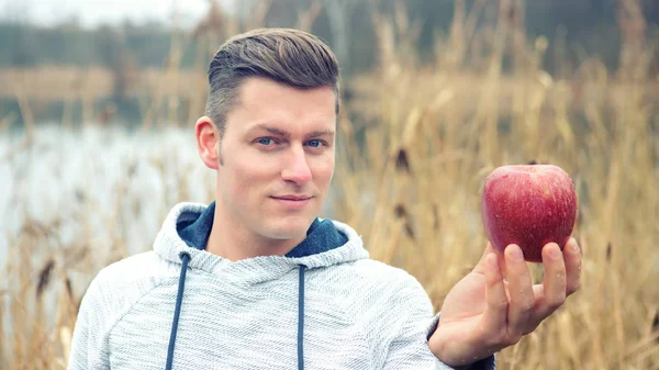 Man outdoors with an apple in his hand — Stock Photo, Image