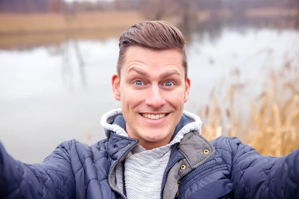 Selfie of handsome blond man in front of lake — Stock Photo, Image
