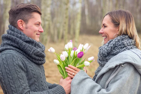 Пара на открытом воздухе с цветами обнимая друг друга — стоковое фото