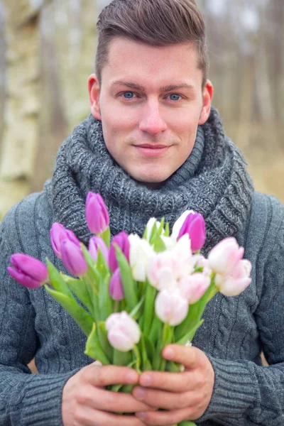 Guapo rubio hombre al aire libre con tulipanes — Foto de Stock