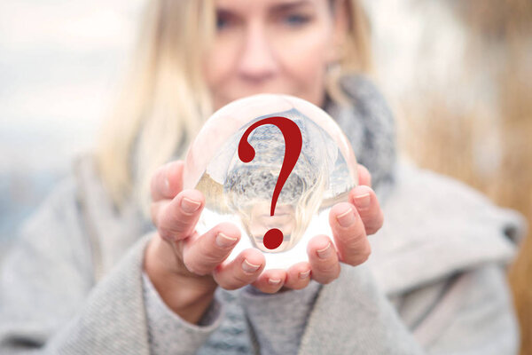 closeup of woman holding glass ball with question mark