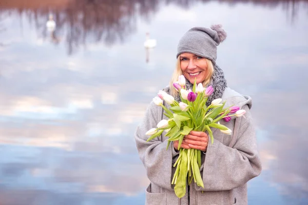 Bella donna con tulipani di fronte al lago — Foto Stock