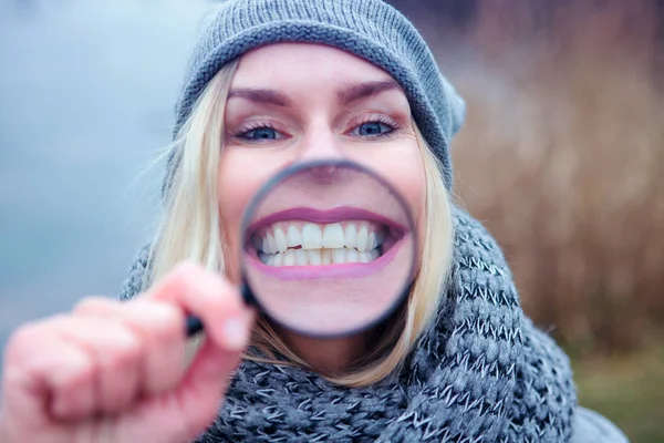 Blond kvinna ler genom ett förstoringsglas — Stockfoto