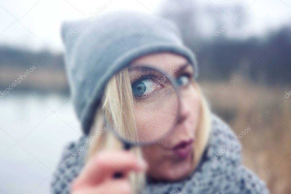 blond woman looking through a magnifying glass