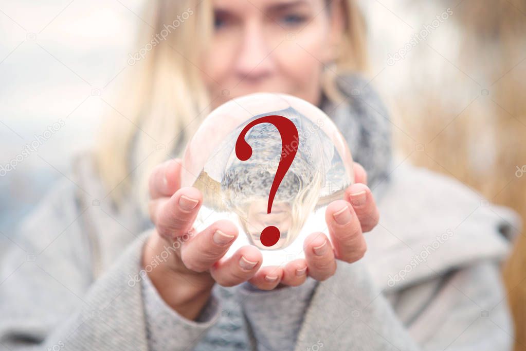 closeup of woman holding glass ball with question mark