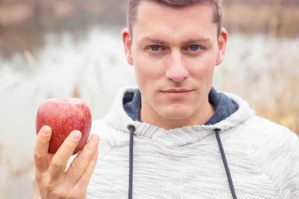 Man outdoors with an apple in his hand — Stock Photo, Image