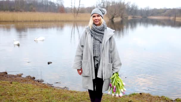 Cinemagraph Blond Kvinna Som Står Framför Sjön Med Bukett Blommor — Stockvideo