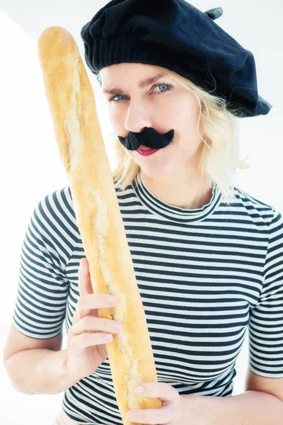 Mujer vestida de hombre francés con bigote y boina sosteniendo bagu — Foto de Stock