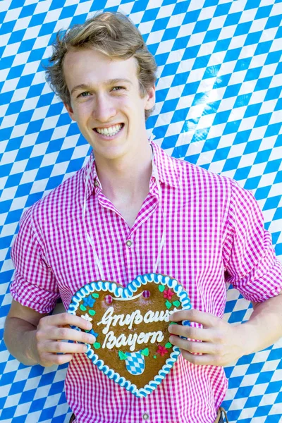 Kalp şeklinde gingerbread tutan Bavyera genç adam — Stok fotoğraf