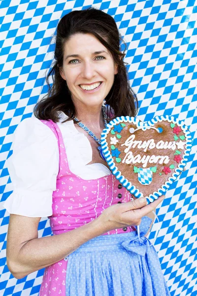 Bavarian woman in dirndl holding a heart-shaped gingerbread — Stock Photo, Image