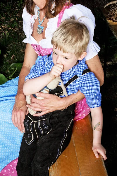 Bavarian chico con madre sentado en banco en beergarden — Foto de Stock