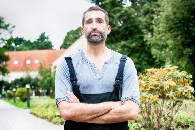 handsome man in dungarees standing outside clipart