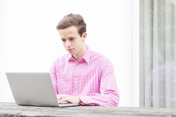 Joven guapo sentado al aire libre con su computadora portátil —  Fotos de Stock